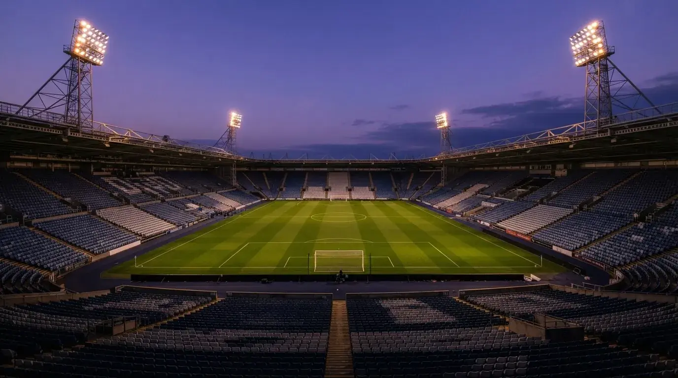An empty football stadium with floodlight masts at dusk
