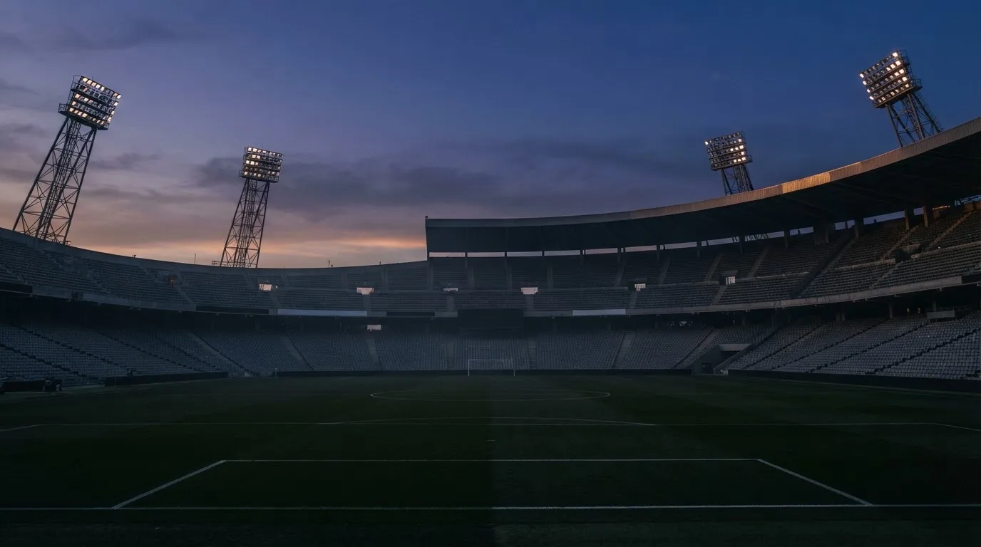 An empty football stadium with floodlight masts at dusk