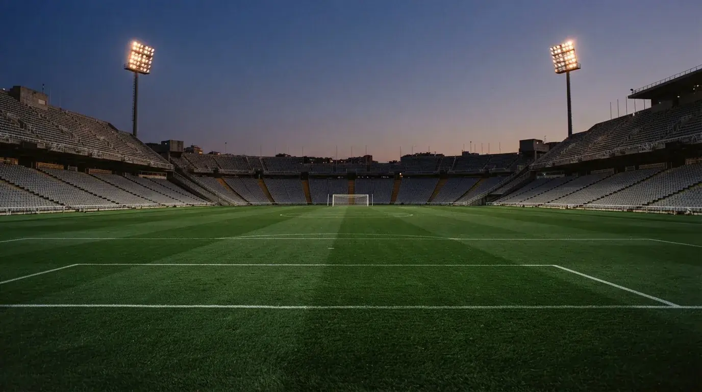 An empty football stadium with floodlight masts at dusk