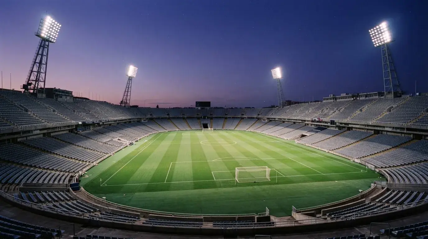 An empty football stadium with floodlight masts at dusk