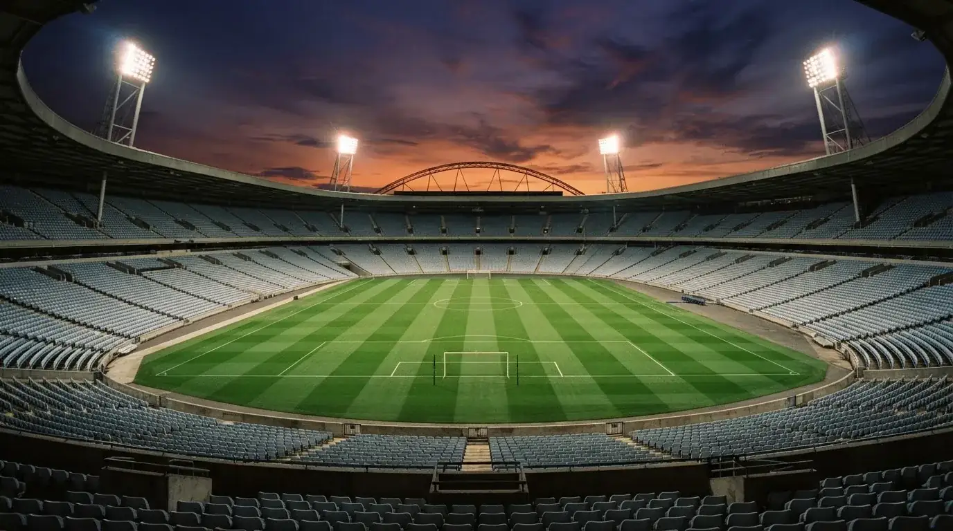 An empty football stadium with floodlight masts at dusk