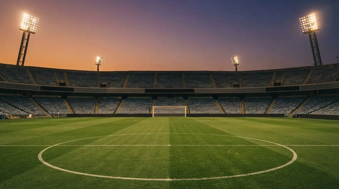 An empty football stadium with floodlight masts at dusk