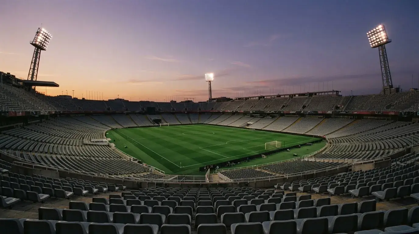 An empty football stadium with floodlight masts at dusk