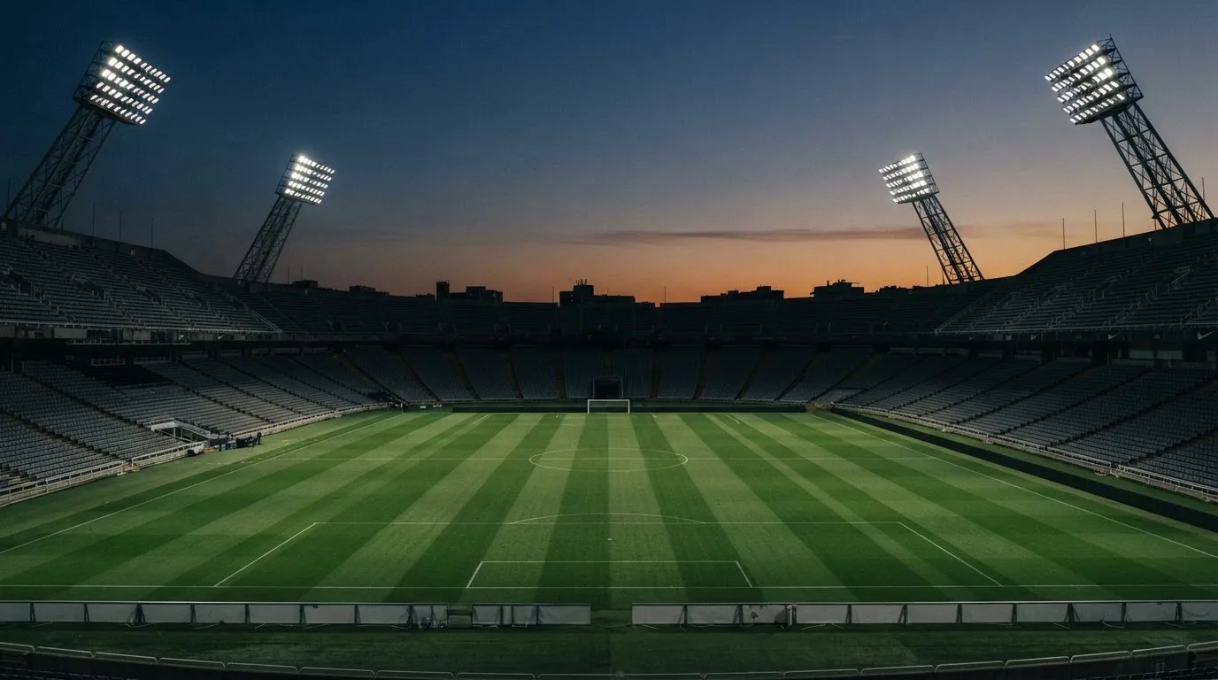 An empty football stadium with floodlight masts at dusk