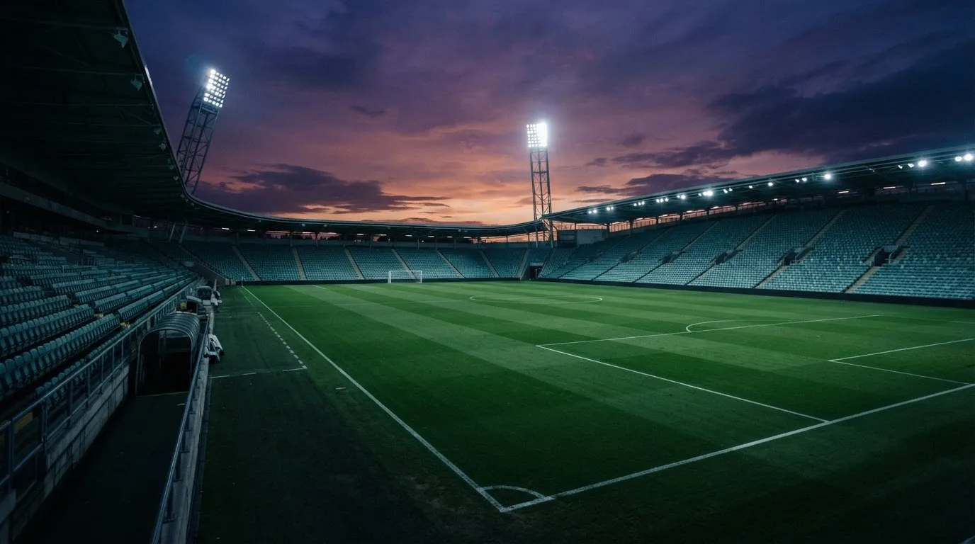 An empty football stadium with floodlight masts at dusk