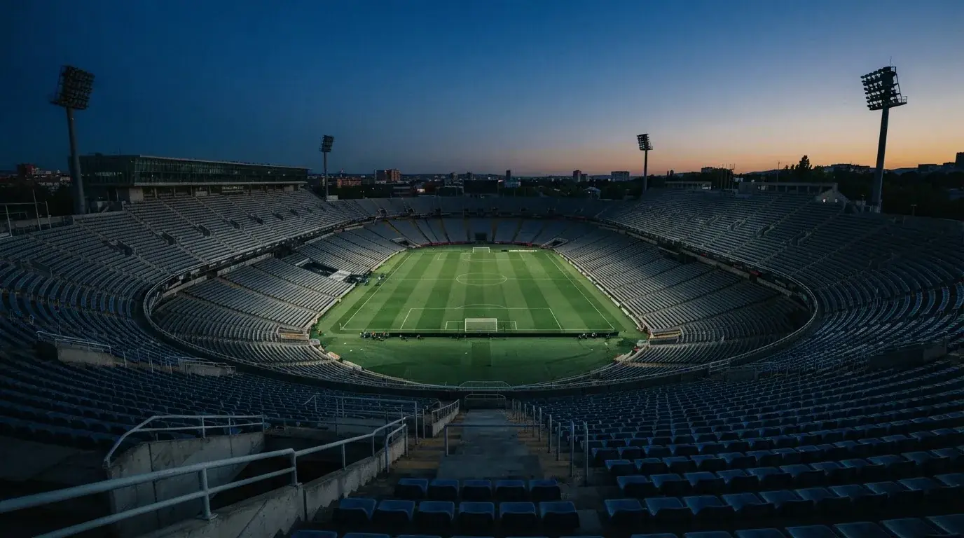 An empty football stadium with floodlight masts at dusk