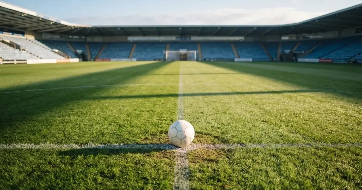 A ball on the centre spot of a grass pitch in morning light