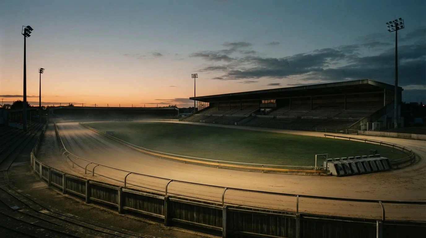 An empty football stadium with floodlight masts at dusk