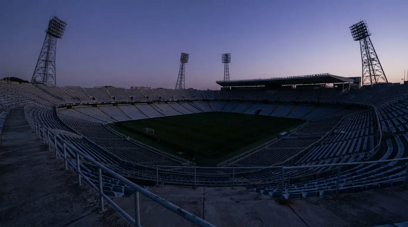 An empty football stadium with floodlight masts at dusk