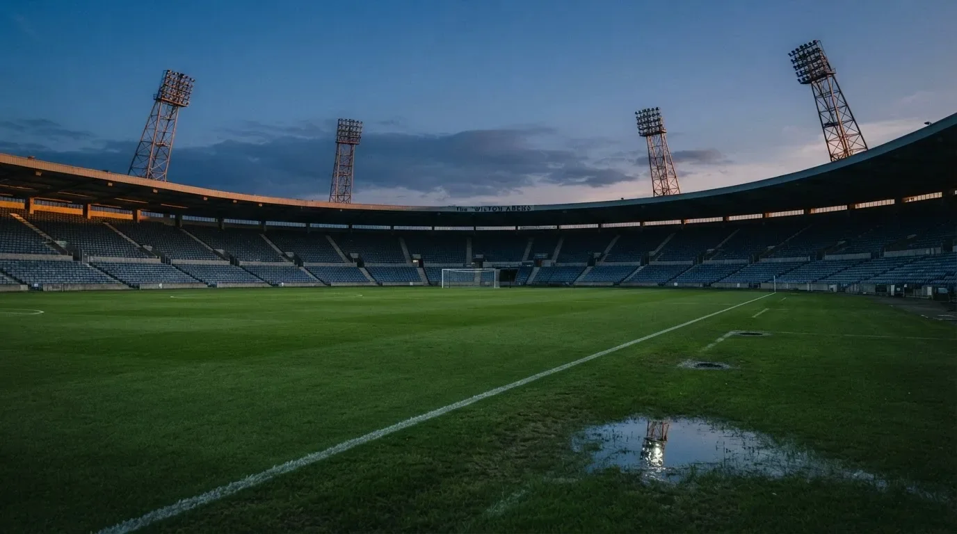 An empty football stadium with floodlight masts at dusk