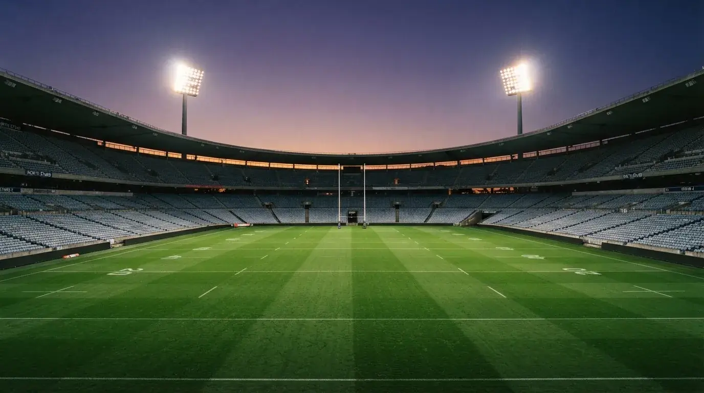 An empty football stadium with floodlight masts at dusk