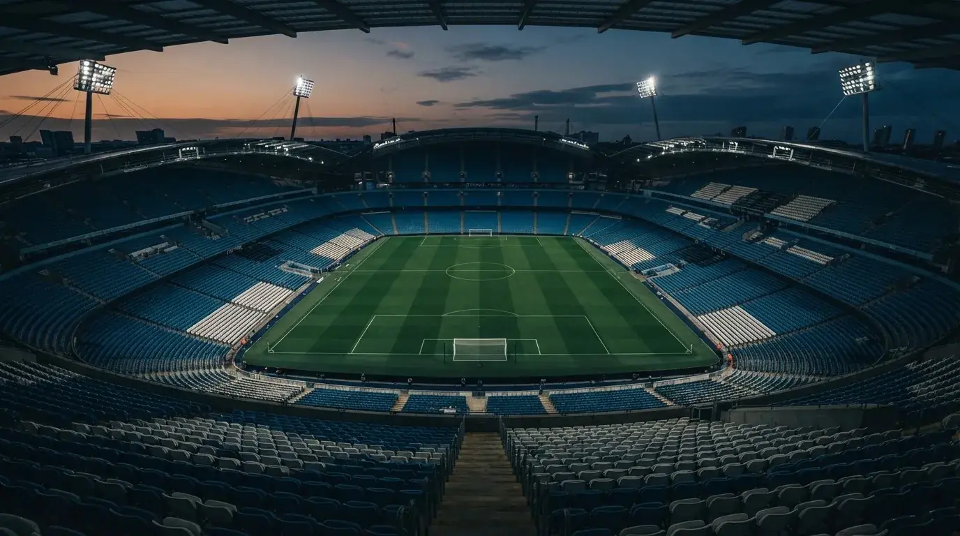 An empty football stadium with floodlight masts at dusk