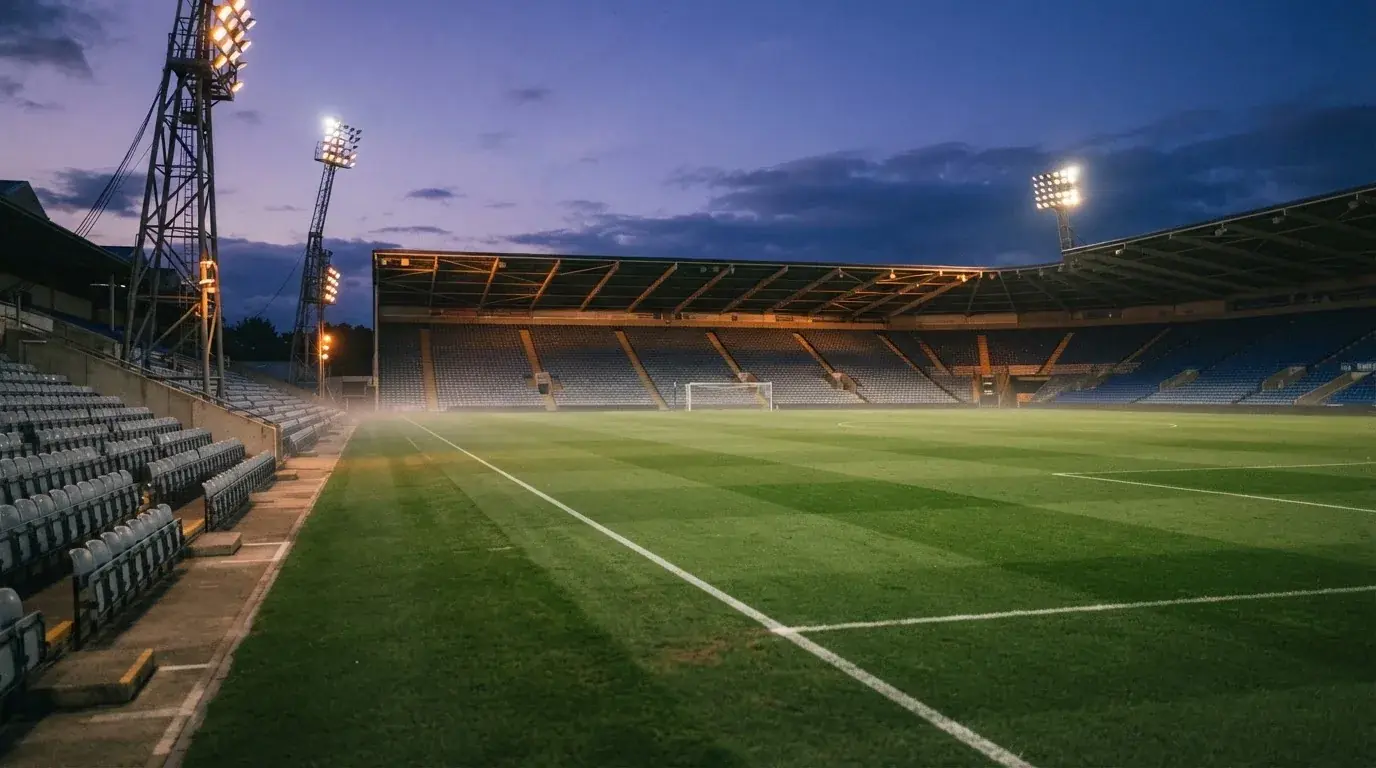 An empty football stadium with floodlight masts at dusk