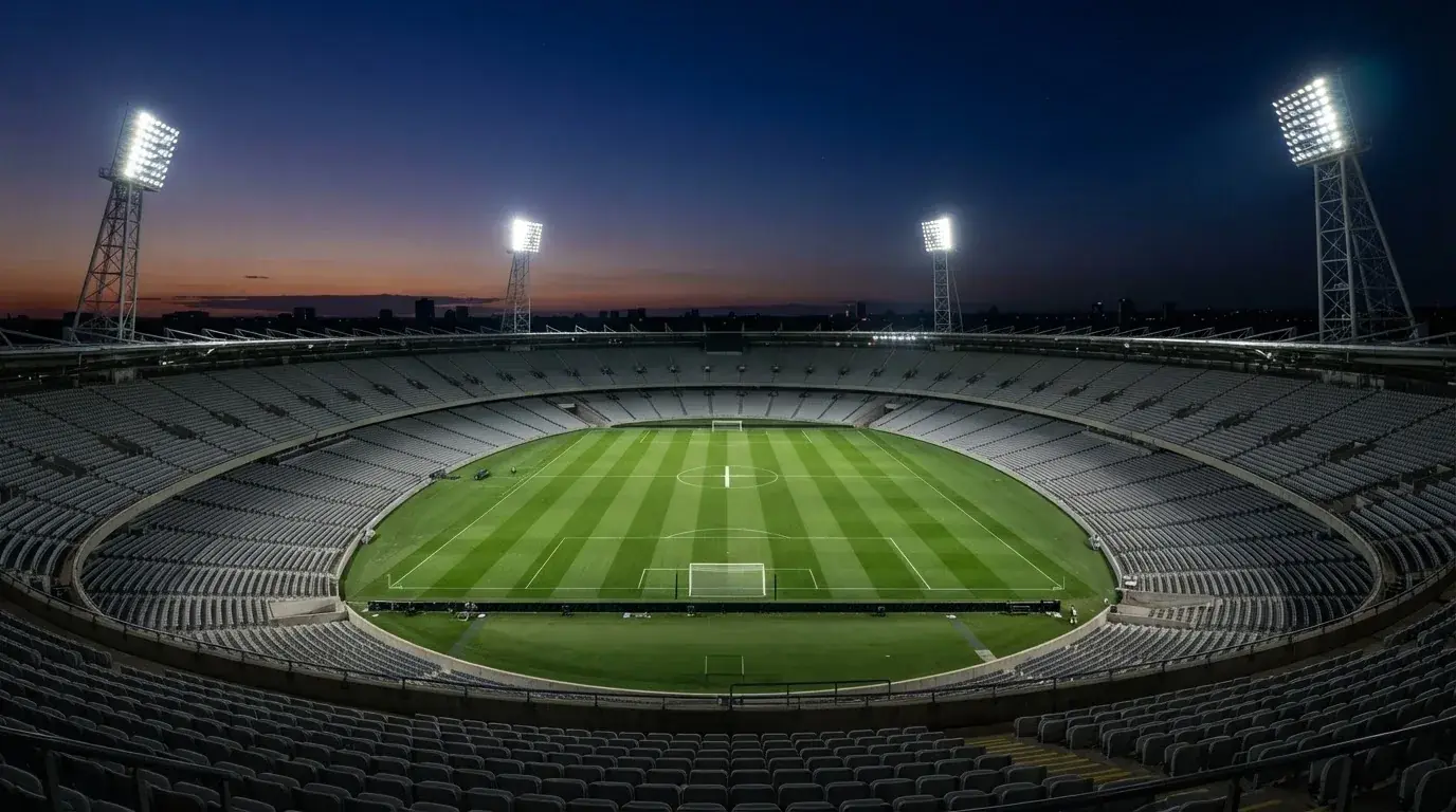 An empty football stadium with floodlight masts at dusk
